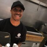 Food service worker behind a counter in a commercial kitchen.