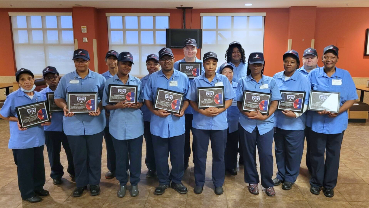 A group of food service workers holding an award and smiling at the camera