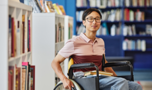 Young man in wheelchair working in a library.