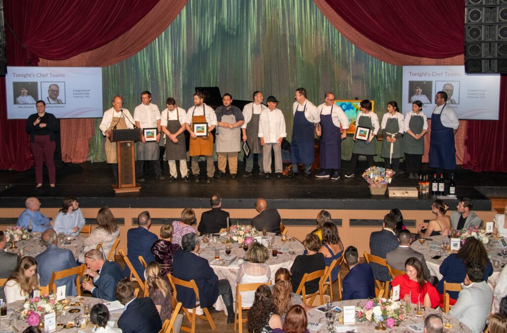 Chefs pose for a group photo on stage